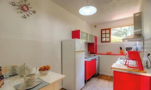 Eine kleine Küche mit Kühlschrank, Mikrowelle und roten Schränken.