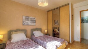 Ein Hotelzimmer mit zwei Betten, einem Spiegel, einer Wand mit einem gerahmten Bild und einer Pendelleuchte.