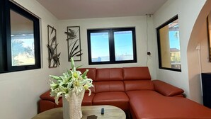 Un salon avec un canapé rouge, une table ronde en bois et un vase de fleurs.