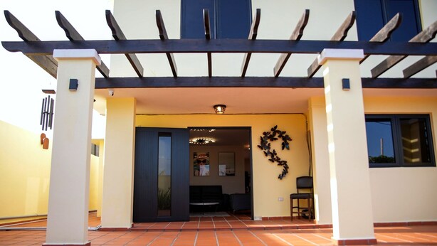 Entrada de un edificio con un patio empedrado, una puerta oscura y un adorno en la pared.