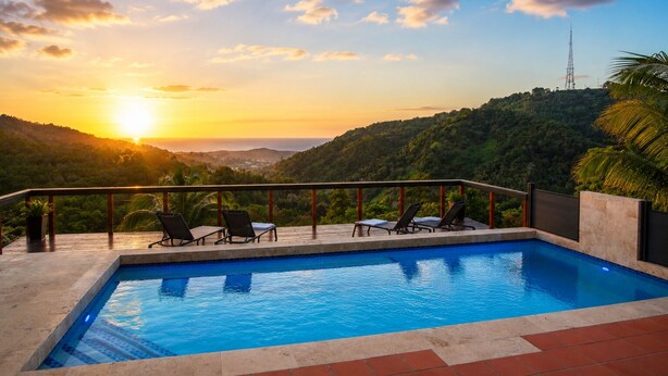Una piscina con vista sul tramonto, sedie a sdraio e una ringhiera.