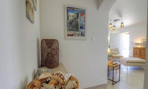 Ein Zimmer mit einem Bett, einem kleinen Tisch mit Lampe, einem an der Wand hängenden Poster und einem Korbwannenkorb.