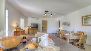 Un soggiorno moderno con zona pranzo, televisione e un'ampia finestra.