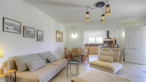 Un soggiorno con divano, tavolo da pranzo e sedie. Si vede una cucina sullo sfondo.