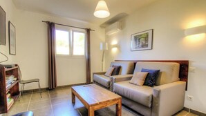 A living room with a sofa, a wooden coffee table, a bookshelf, and a window with curtains. - U Castagnu 2 - EVISA (EVISA)