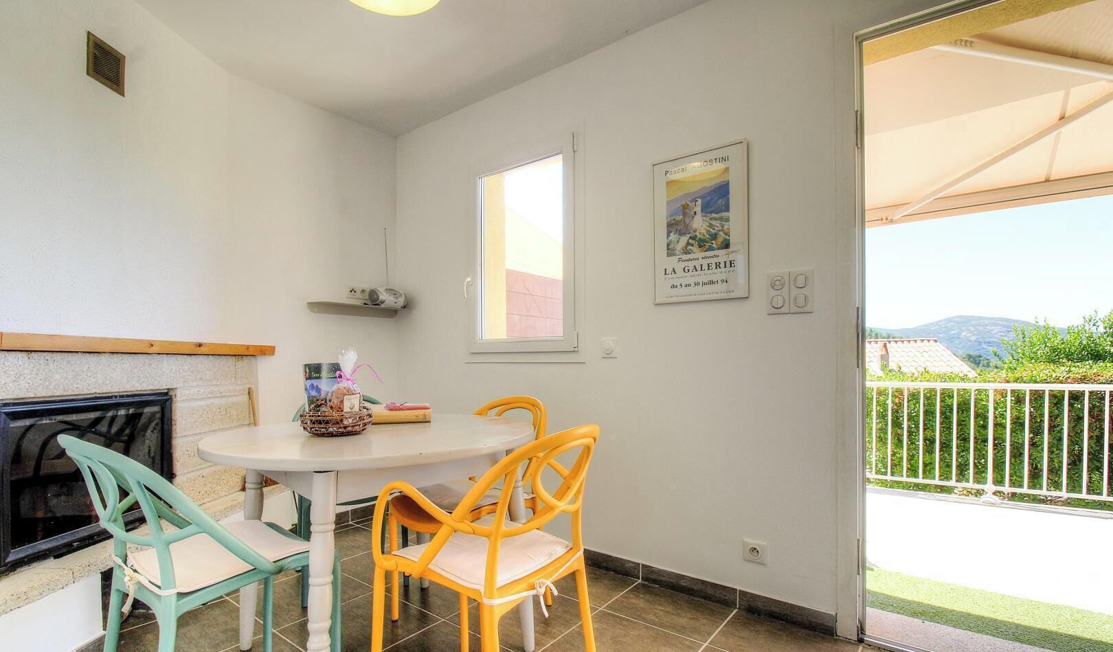 Un petit coin repas avec une table et des chaises, une cheminée, une fenêtre et un balcon offrant une vue.
