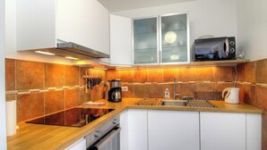 A modern kitchen with a wooden countertop, stainless steel appliances, and a backsplash of orange tiles. - U Castagnu 2 - EVISA (EVISA)