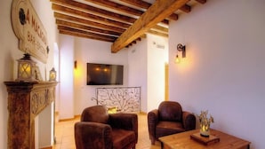 A living room with a wooden ceiling, leather sofas, a TV, and a bar sign. - A Torra - CATERI - Gîte (CATERI)