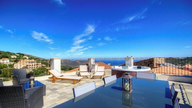 A rooftop terrace with a glass table, wicker chairs, a hot tub, and a scenic view of the coastline. - A Torra - CATERI - Gîte (CATERI)