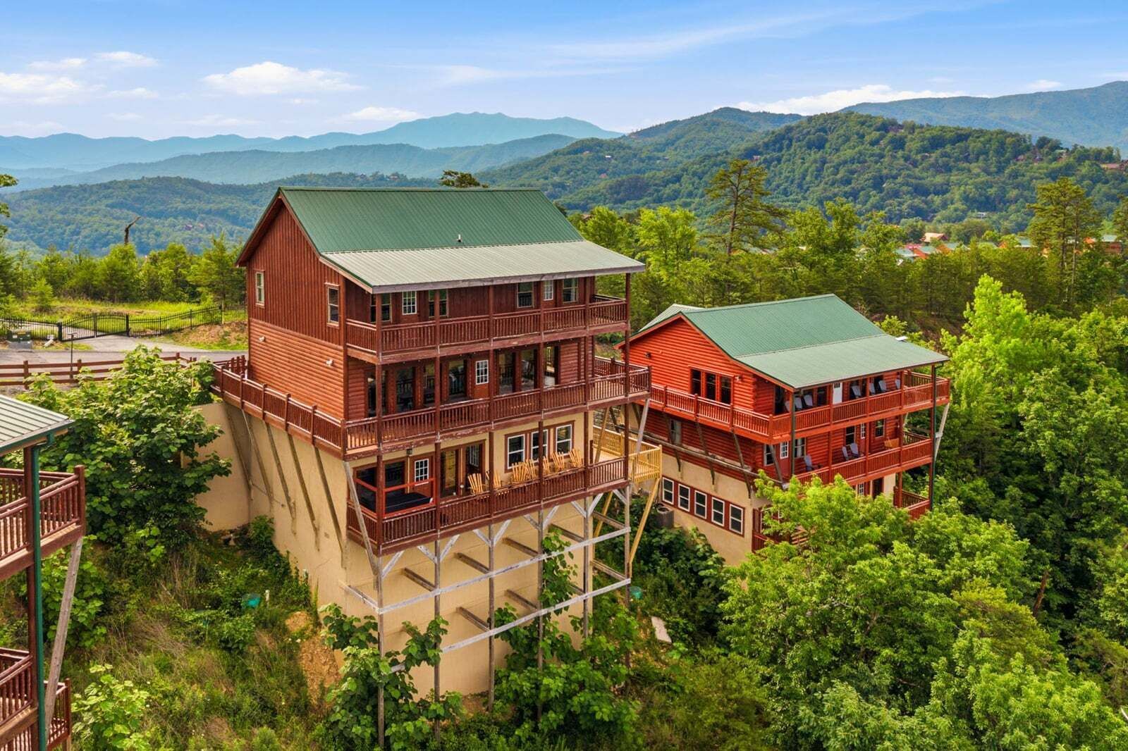 Un edificio de varios pisos con balcones, rodeado de abundante vegetación y montañas.