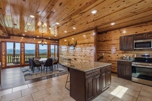A wooden interior with a kitchen, dining area, and large windows overlooking a scenic view. - Zennessee Luxe・IndoorPool・MtnViews・HotTub・Theater・EVCharger・PetsWelc (Sevierville)