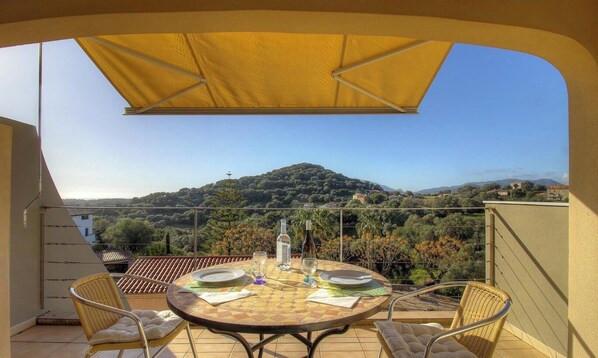 A balcony with a table set for two, a wicker chair, and a yellow umbrella. - Amandine - BASTELICACCIA (BASTELICACCIA)