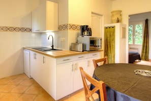 Cocina compacta con lavamanos, estufa, microondas y tostadora. Hay una mesa de comedor con sillas.