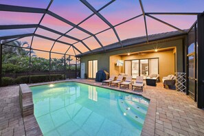 Ein Schwimmbecken mit Liegestühlen und einer überdachten Terrasse.
