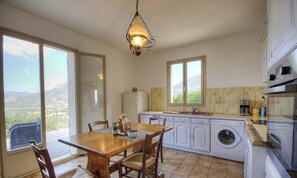 A kitchen with a dining table, chairs, a washing machine, a refrigerator, and a view of the outdoors. - Appulatoddiu - CANNELLE D'ORCINO (CANNELLE D'ORCINO)
