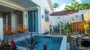 Un espace piscine aménagé avec des chaises, une table et une clôture en bois.