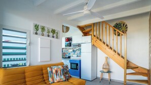 Un espace de vie moderne comprenant un canapé, un escalier, une cuisine et une vue par la fenêtre.