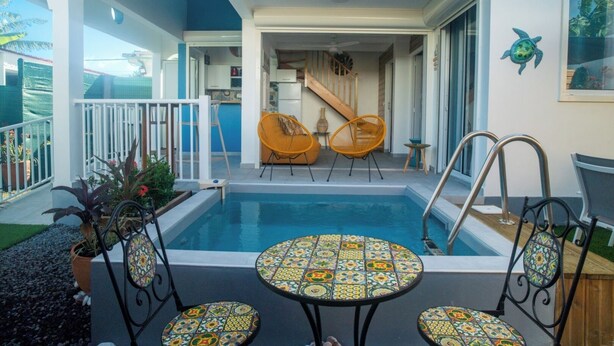 Un espace piscine avec une table et des chaises, un escalier et une vue sur l’intérieur.