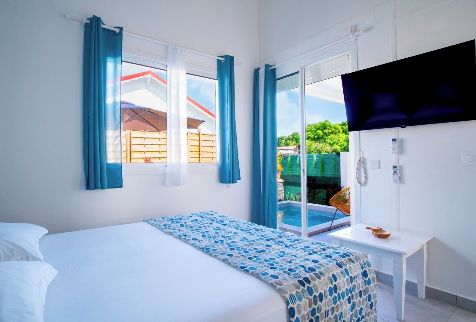 Une chambre avec un lit, une télévision, une petite table et une vue sur une piscine et un espace verdoyant.