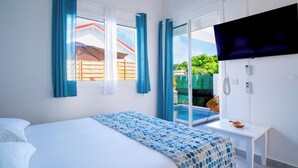 Une chambre avec un lit, une télévision, une petite table et une vue sur une piscine et un espace verdoyant.