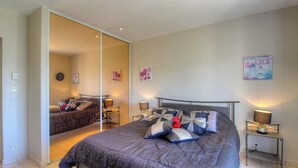 Ein Schlafzimmer mit einem Bett, Nachttischen, einem Spiegel und Wandbildern.