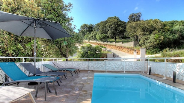 Ein Poolbereich mit Liegestühlen und einem großen Sonnenschirm.