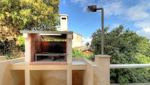 Eine Grillanlage im Freien mit Backofen, Metallzaun und einer Straßenlaterne.