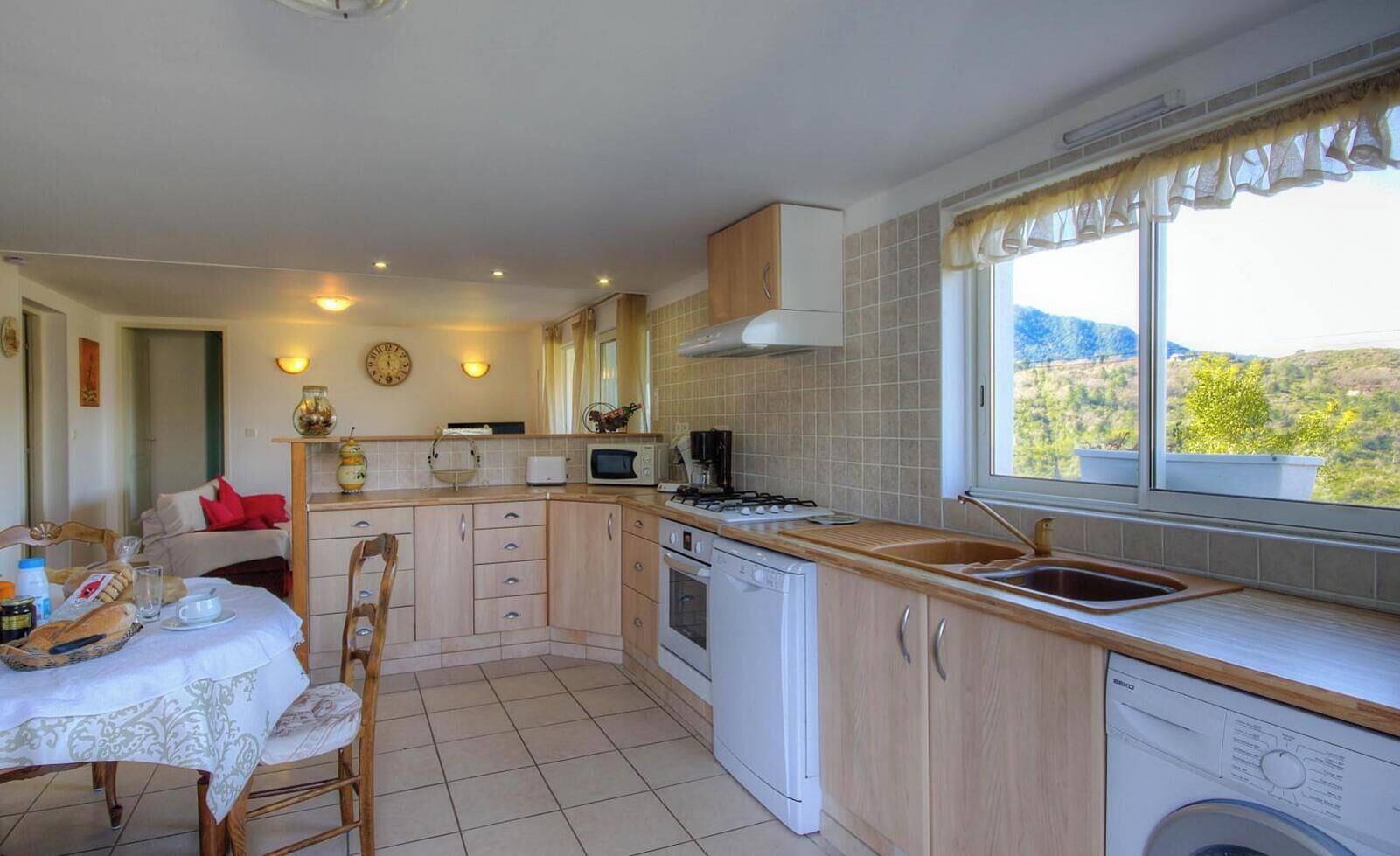 A compact kitchen with a dining area, a washing machine, and a window with a view of the outdoors.