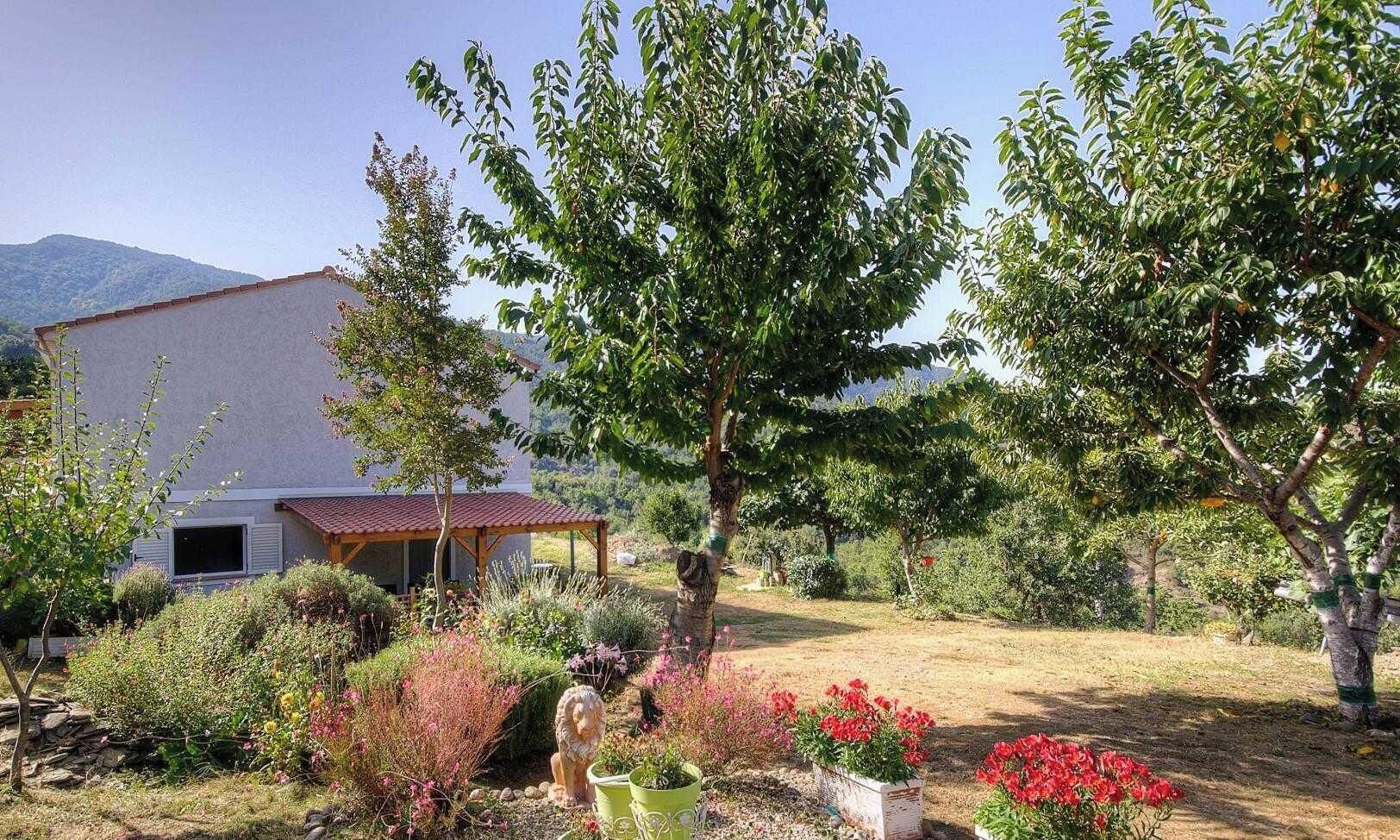 A house with a garden, a gazebo, and a mountain in the background.