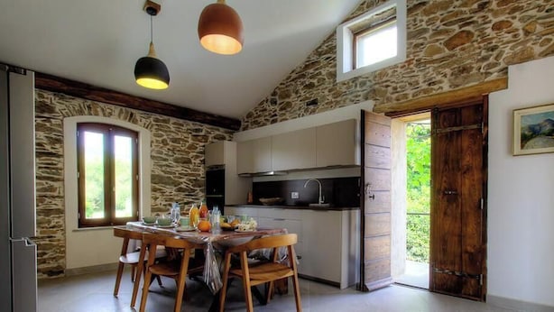 Uma cozinha rústica com paredes de pedra, móveis de madeira e um espaço de jantar com mesa e cadeiras.