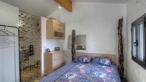Une chambre à coucher avec un lit, une commode en bois, un luminaire suspendu et une fenêtre.