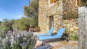 A stone building with a wooden gate, two blue lounge chairs, and purple flowers. - Casa Sola - CARGESE - Guest house (CARGESE)