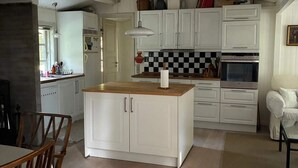 Een keuken met witte kasten, een houten kookeiland, een geruit spatwand en een hangende lamp.