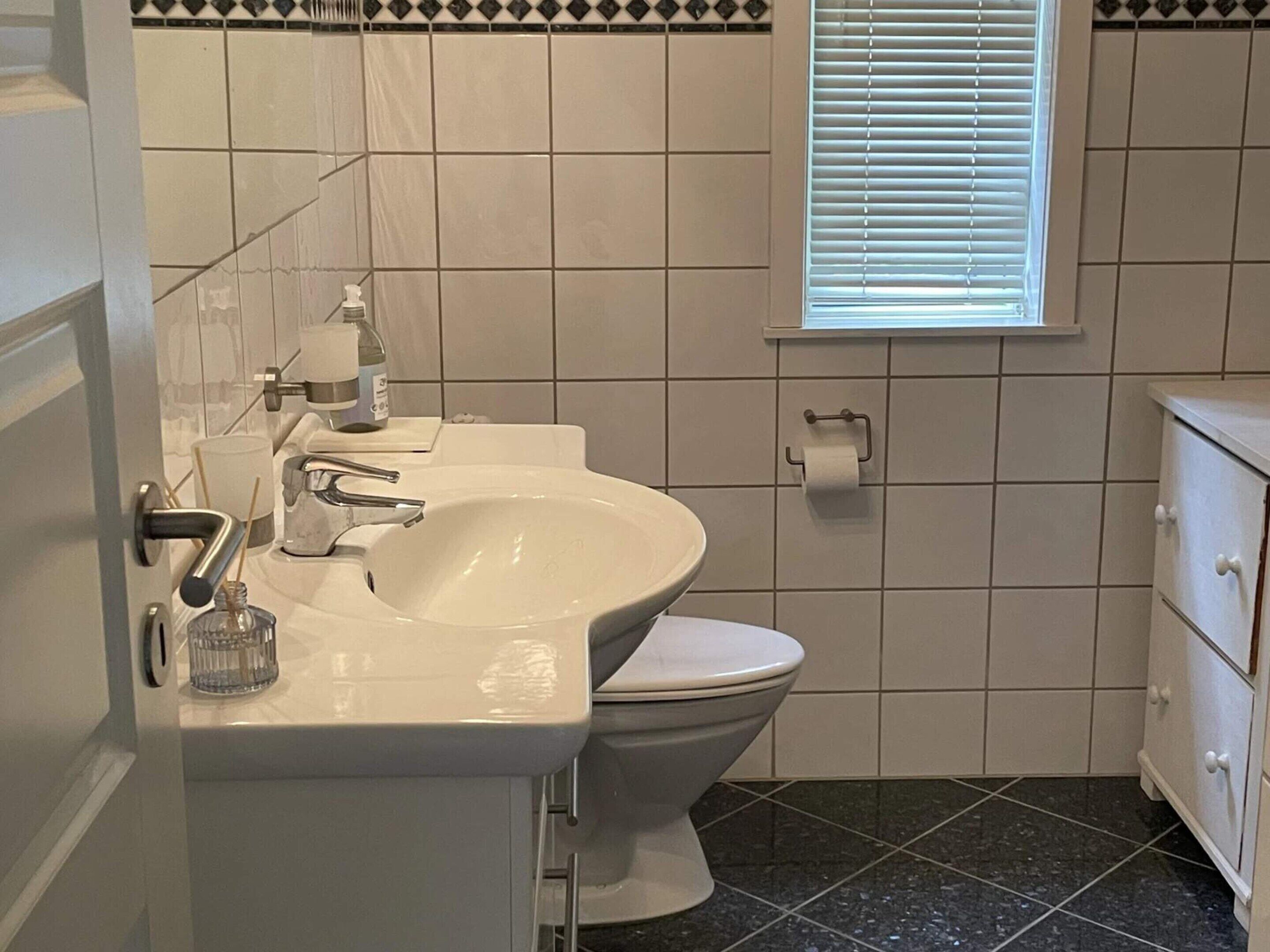 Ein Badezimmer mit weißem Waschbecken, Toilette und Schminktisch mit Schubladen.