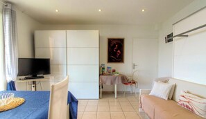 Ein Wohnzimmer mit Fernseher, Esstisch und Sofa.