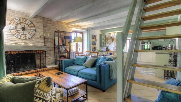 Ein Wohnzimmer mit Kamin, einem blauen Sofa, einem Holztisch und einer Treppe.