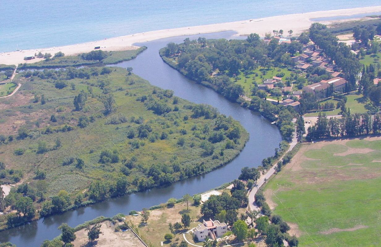 Vista aérea de un río que atraviesa una zona residencial con casas y vegetación.
