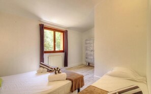 Ein Schlafzimmer mit zwei Betten, einem Heizkörper, einem Fenster mit Vorhängen und einem Kleiderschrank.