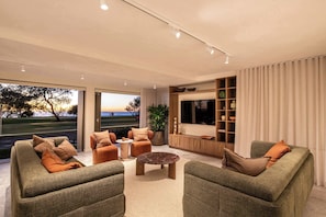 A modern living room with a sofa set, a coffee table, a TV, and a bookshelf. - Monkirra One (Miami)