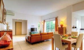 Ein geräumiges Wohnzimmer mit Sofa, Esstisch und Fernseher.