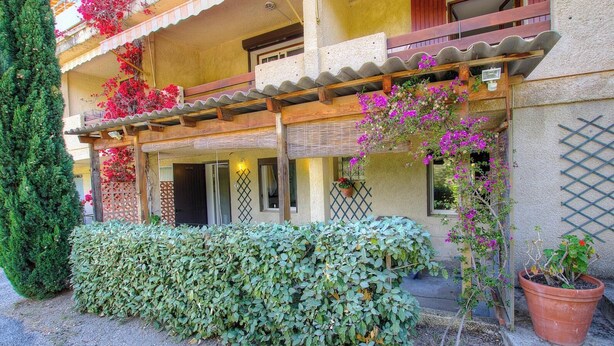 Ein Gebäude mit überdachter Veranda, Holzbalkon und Kübelpflanzen.