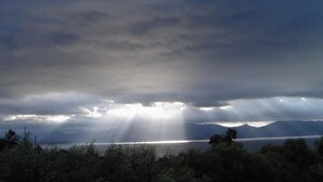 Eine Küstenlandschaft mit Bergen, einem Gewässer und einem bewölkten Himmel.