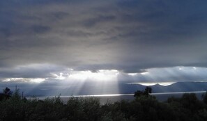 Eine Küstenlandschaft mit Bergen, einem Gewässer und einem bewölkten Himmel.