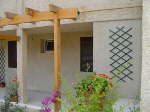 Ein Gebäude mit einer Holzpergola, einem Gitterfenster und Pflanzkübeln.