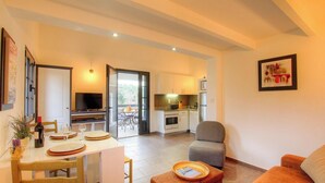 Amplia sala de estar con comedor, cocina y puerta corrediza de vidrio que da a un balcón.