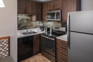 Una cucina con mobili in legno, elettrodomestici in acciaio inossidabile, lavastoviglie e macchina da caffè.