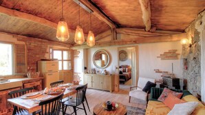 Una cocina rústica con comedor, techo de madera y un espacio de sala acogedor con sofá y una mesa de centro redonda.