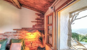 Una habitación acogedora con pared de ladrillo, techo de madera y ventana con vistas al paisaje.