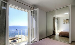 Una habitación con balcón, una cama, un espejo y un cuadro.