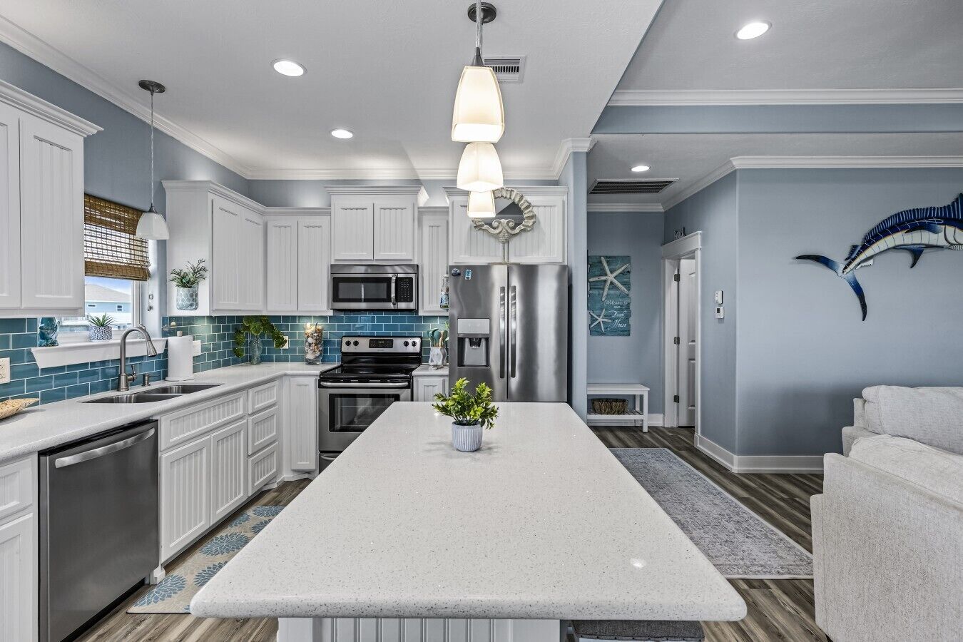 A modern kitchen with white cabinets, stainless steel appliances, and a central island.